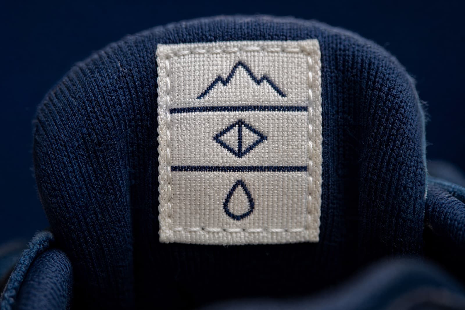 Macro photograph of a stitched fabric label showing three rows of pictogram symbols